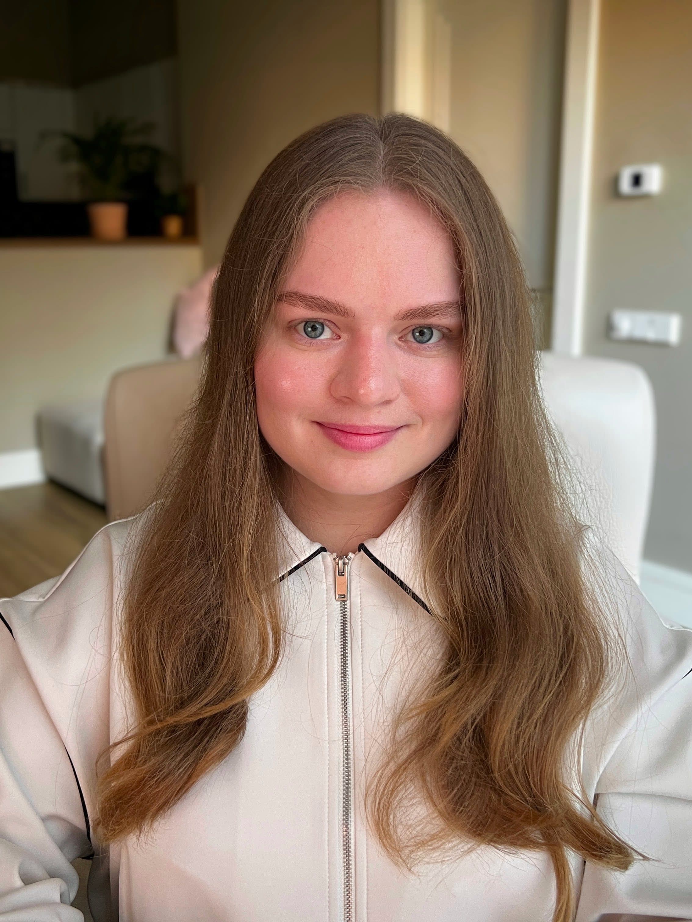 Portrait of Ana, smiling, wearing a white jacket